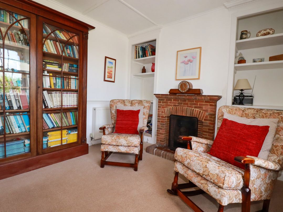 A living room with bookshelves and armchairs at Penrose Farm Cottage St Keverne