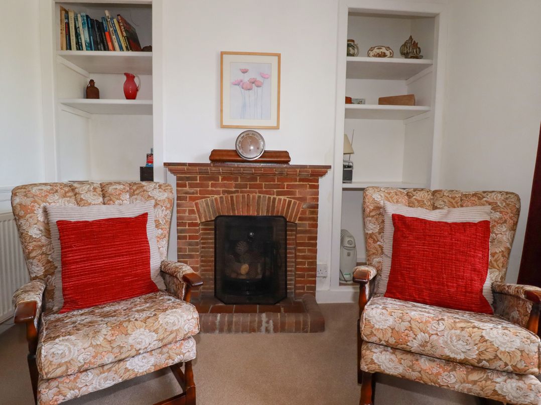 A sitting room with two armchairs and a fireplace at Penrose Farm Cottage St Keverne