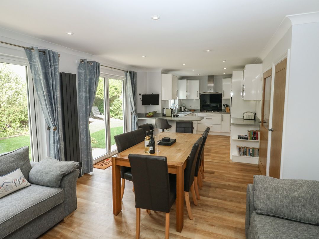 A living room with a dining table and kitchen area at Glebe House in Bigbury