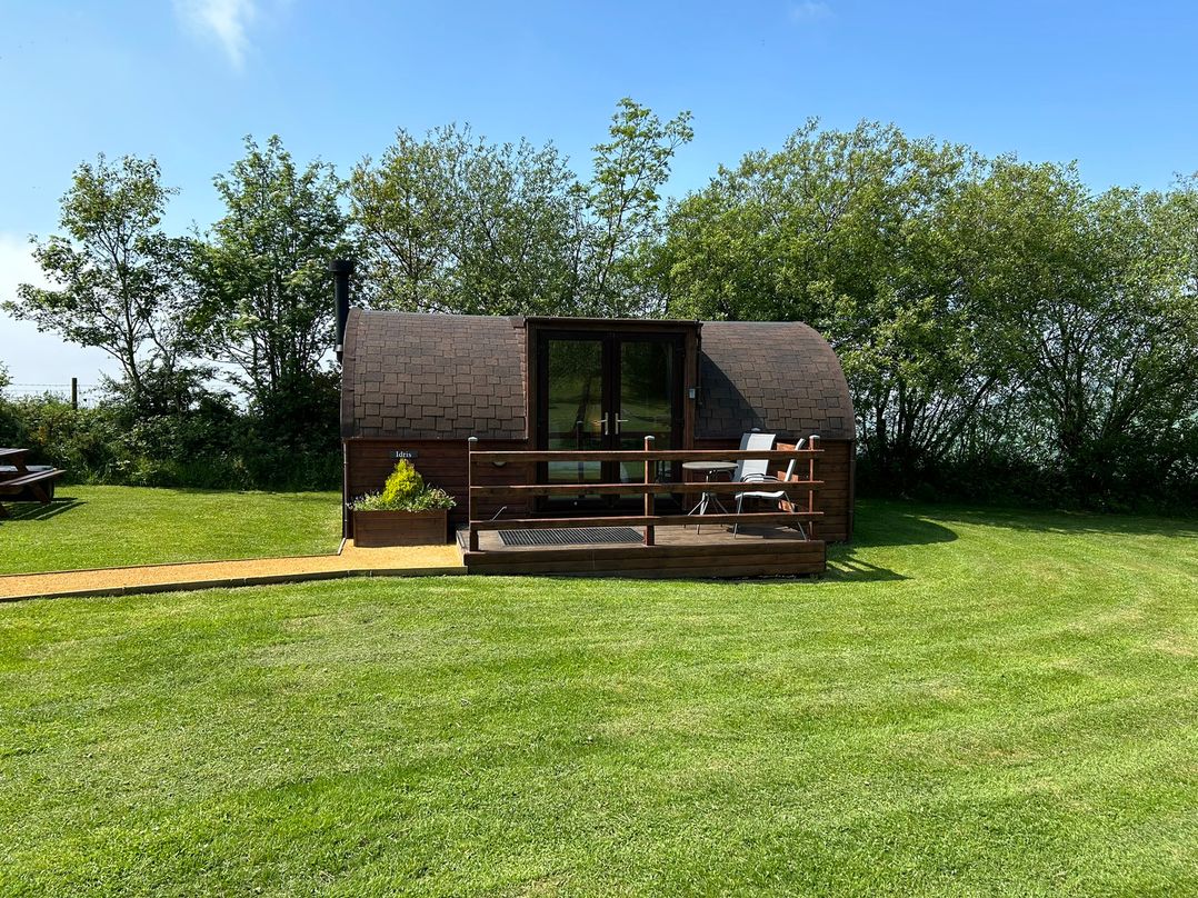 A wooden pod with decking and furniture at Gelert Pod St Asaph