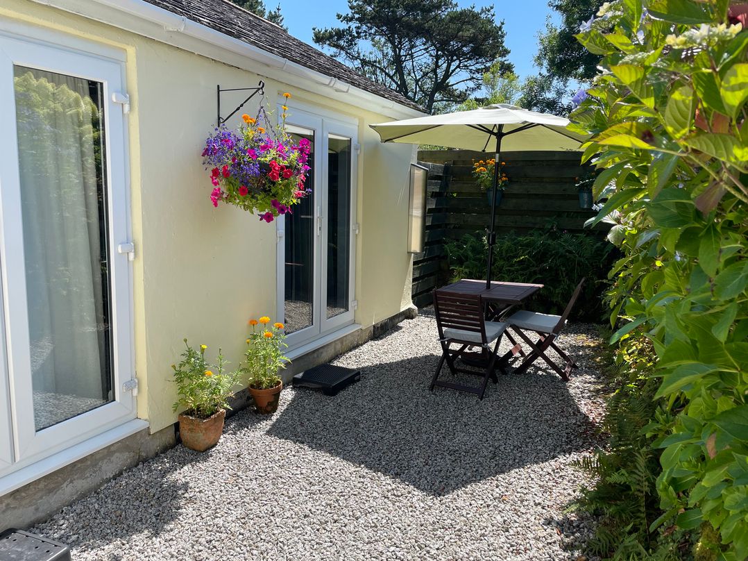 An outdoor seating area with a table and chairs at Garden Cottage in St Just