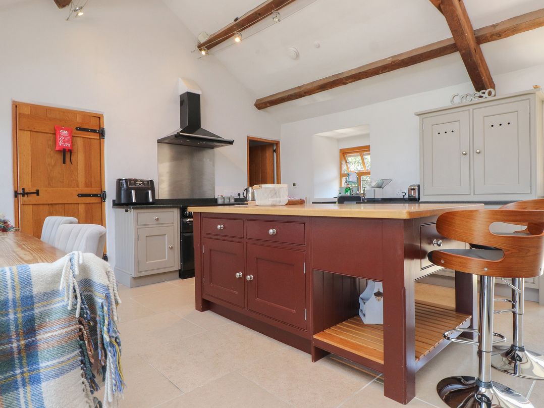 A kitchen with a kitchen island and stools at Wern Olau Cottage Groeslon near Caernarfon