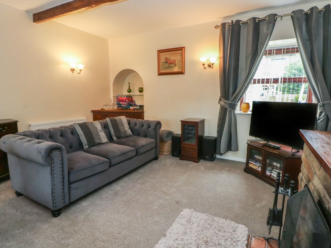 A living room with a sofa, television, and bookshelf at West End House Thornton, West Yorkshire