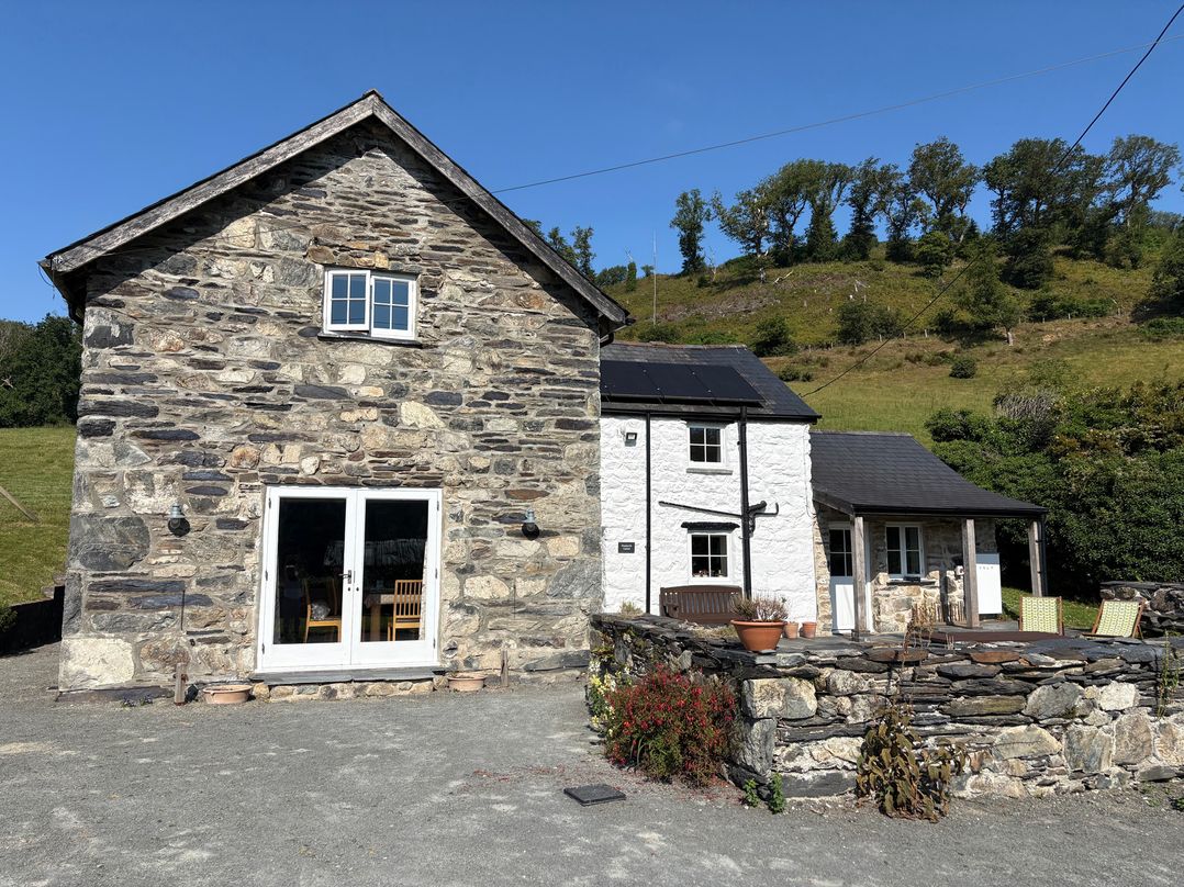 A house with stone walls and patio seating at Peniarth Ganol in Tywyn