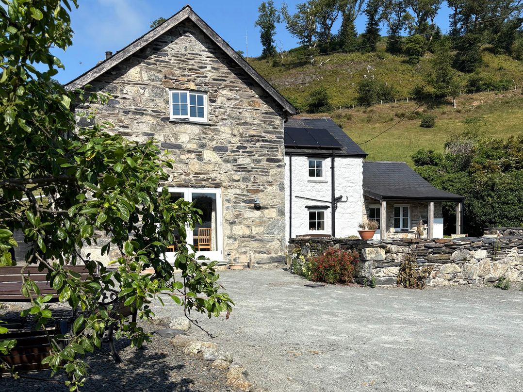 A stone house with solar panels and gravel driveway at Peniarth Ganol in Tywyn