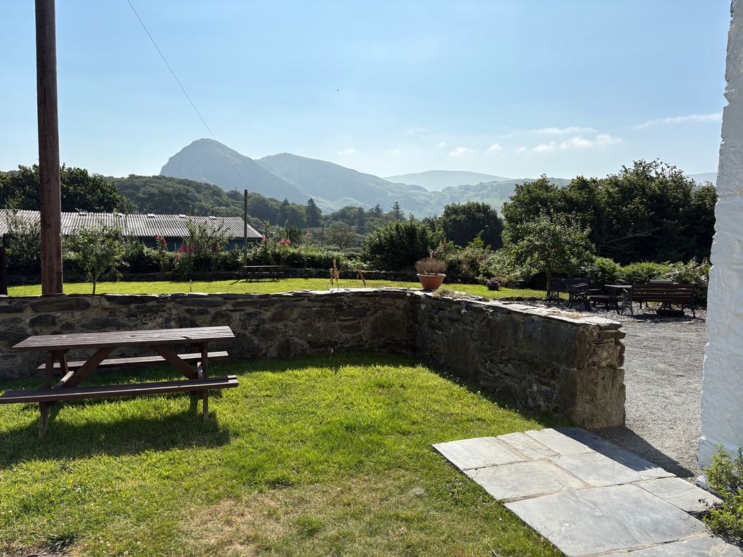 An outdoor area with a picnic table and mountains in the background at Peniarth Ganol in Tywyn