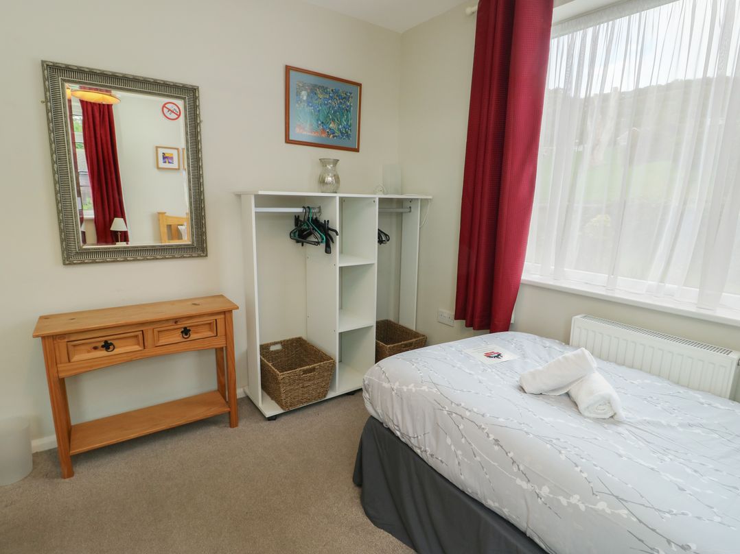 A bedroom with a bed, mirror, and clothing storage at Awelon Rhos-On-Sea