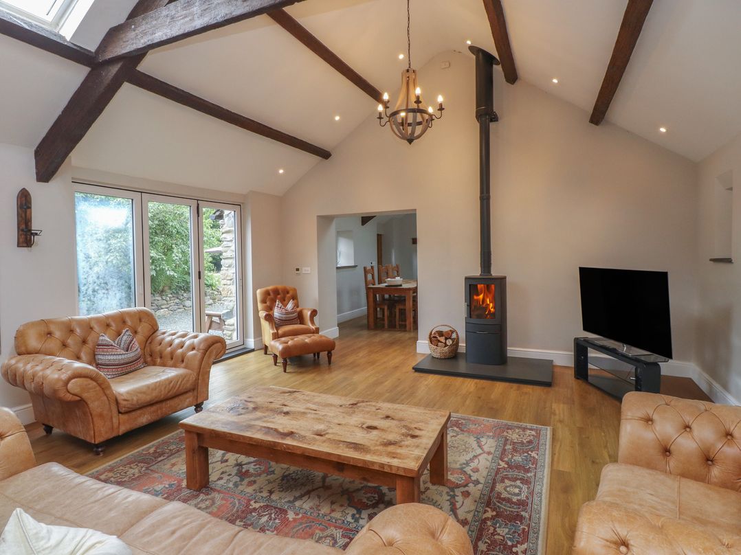 A living room with a fireplace and seating area at Beudy'r Wennol in Groeslon