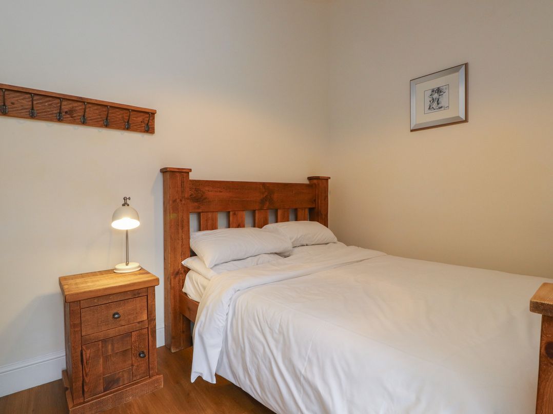 A bedroom with a bed and lamp at Beudy'r Wennol in Groeslon