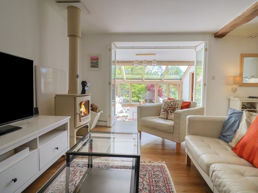 A living room with a wood stove and glass door to the garden at Pottery Barn in Branscombe