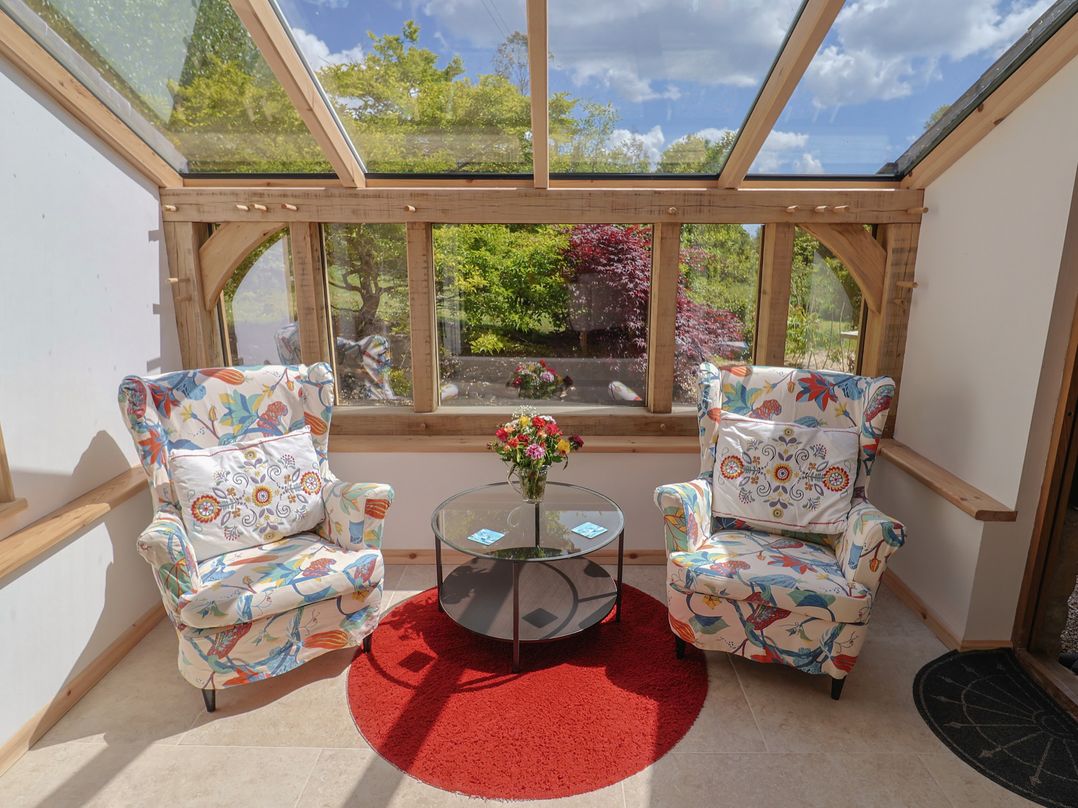 A conservatory with chairs and a table at Pottery Barn in Branscombe