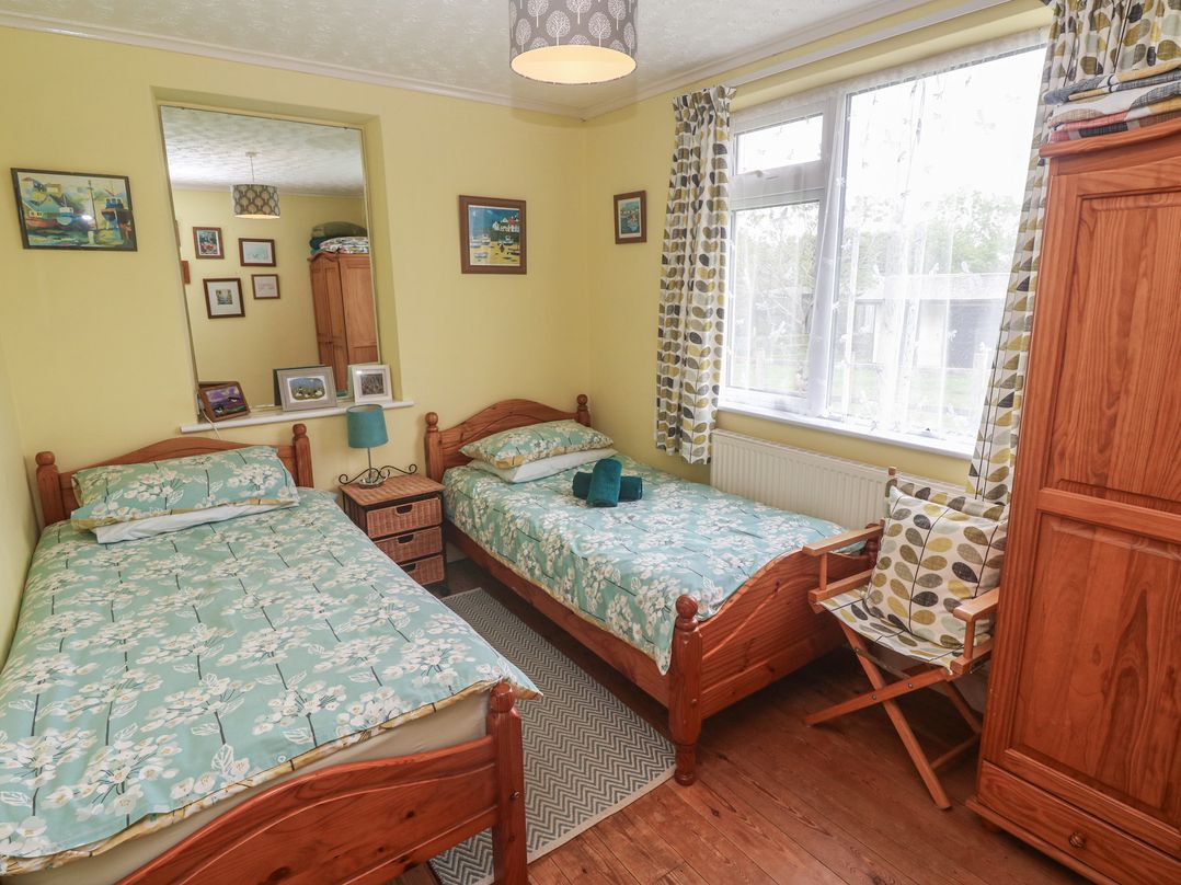 A bedroom with two beds and a wardrobe at Woolly Welcome Goldsithney
