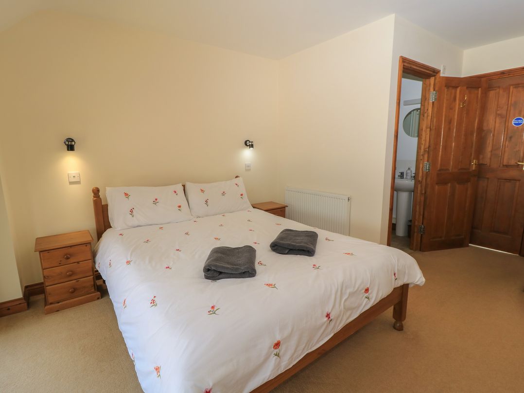 A bedroom with a bed and bedside tables at Tithe Barn, Lyneham