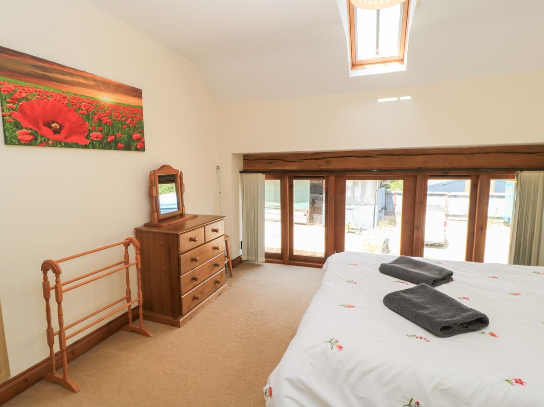 A bedroom with a bed and dresser at Tithe Barn, Lyneham