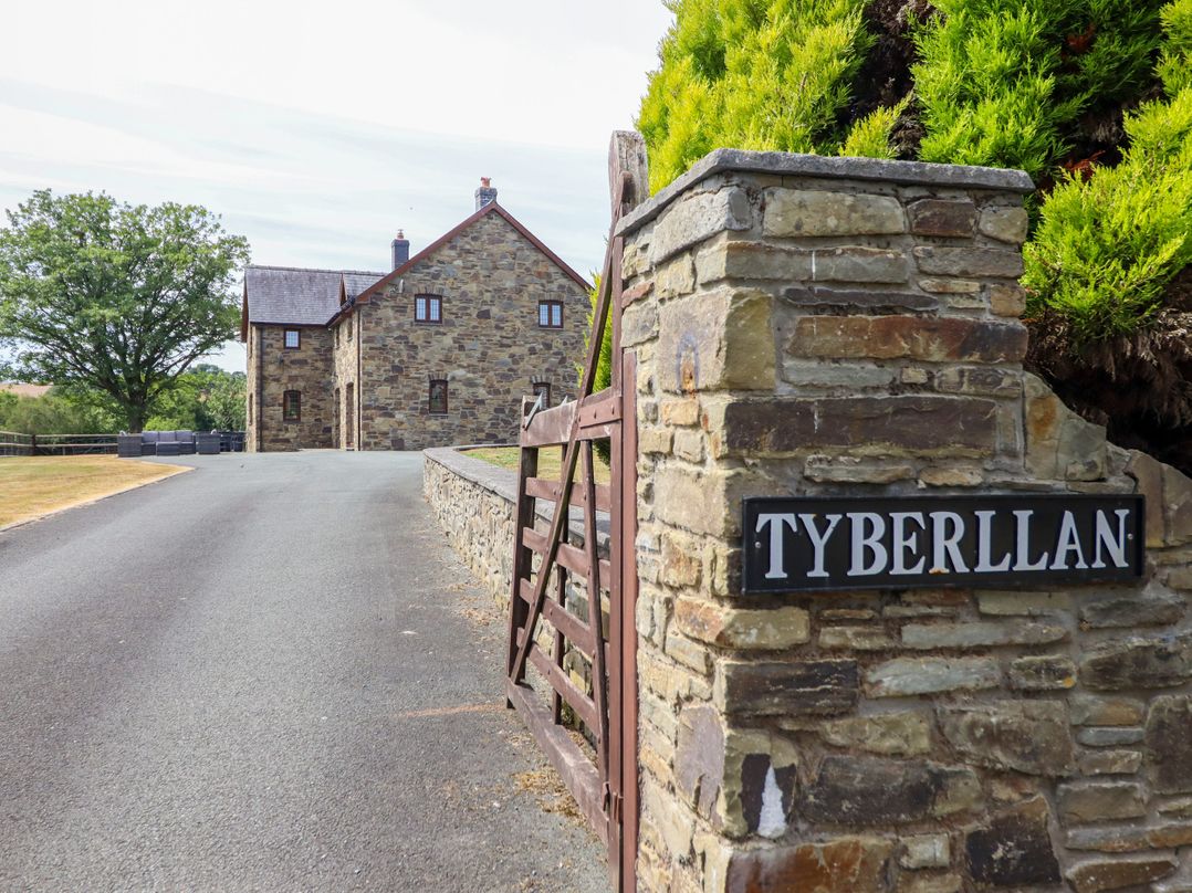 A stone house with a driveway and gate at Ty Berllan in Caersws