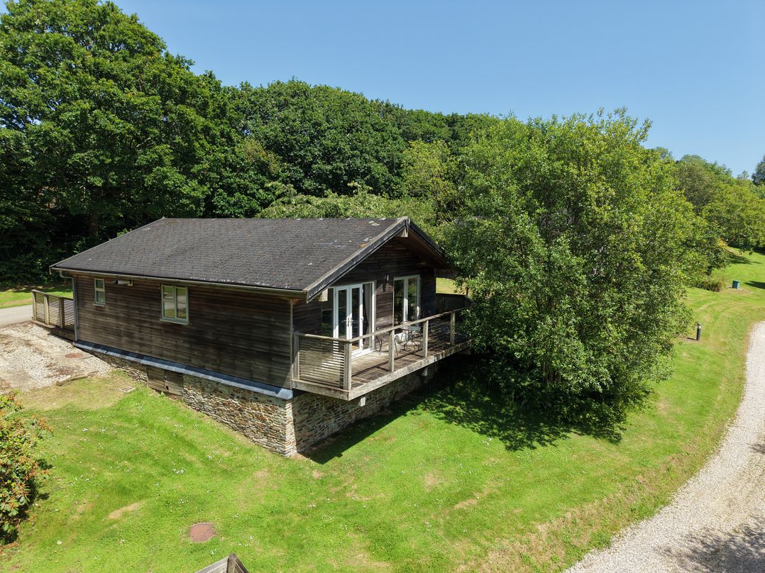 A house with a deck in a grassy area at 1 Lake View in Lanreath