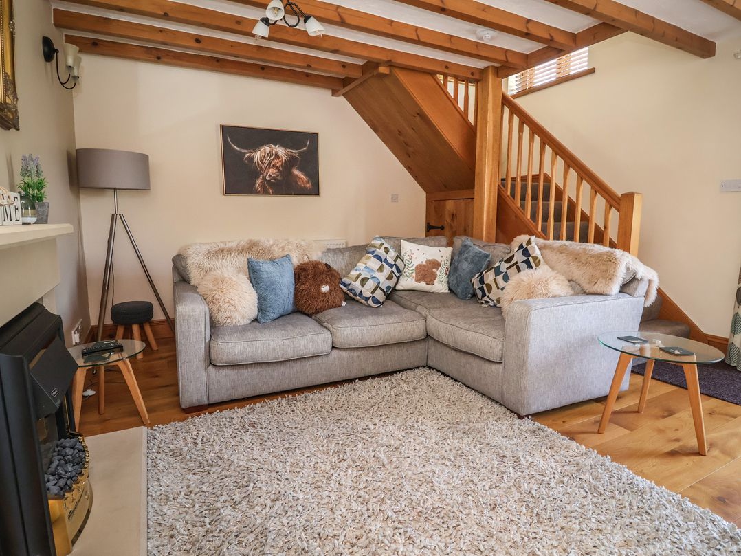 A living room with a sofa and a staircase at Ash Farm Cottage in Lixwm near Caerwys