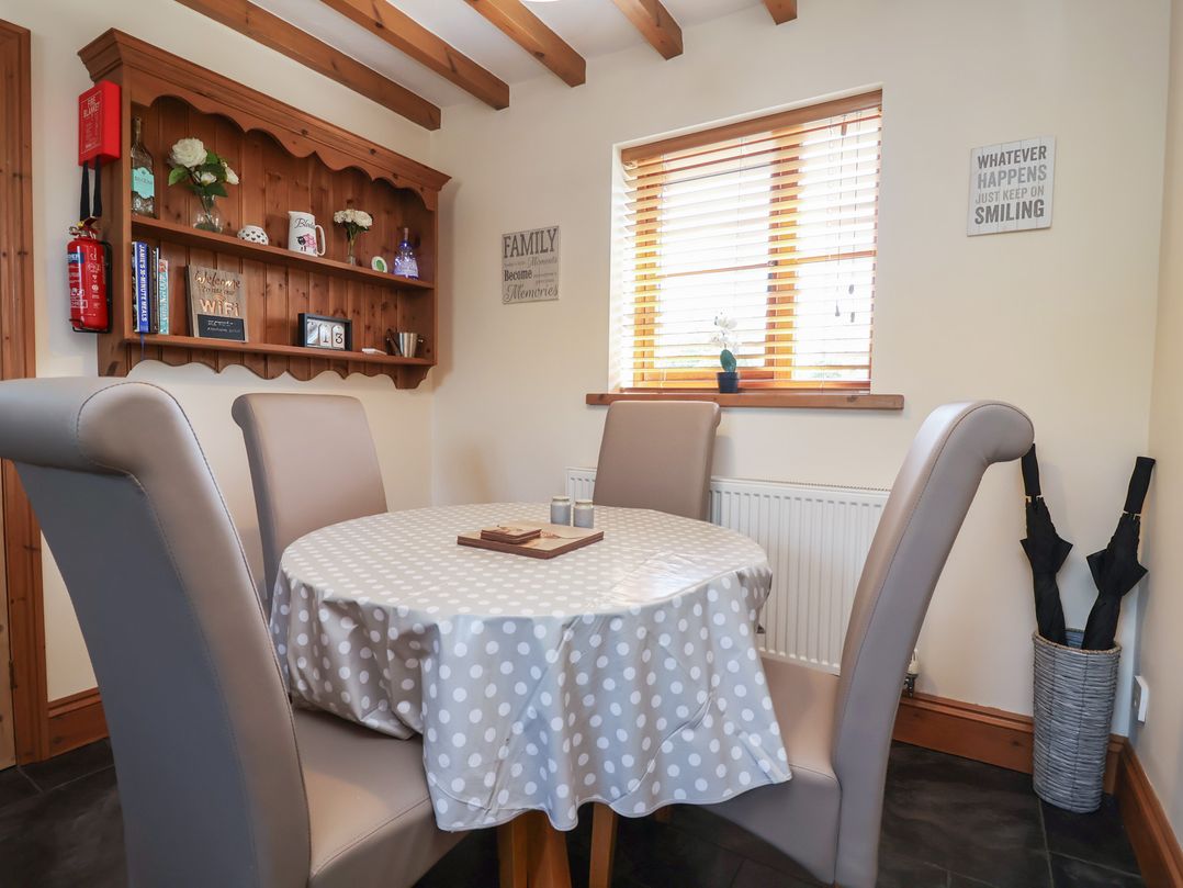 A dining room with a round table and chairs at Ash Farm Cottage in Lixwm near Caerwys