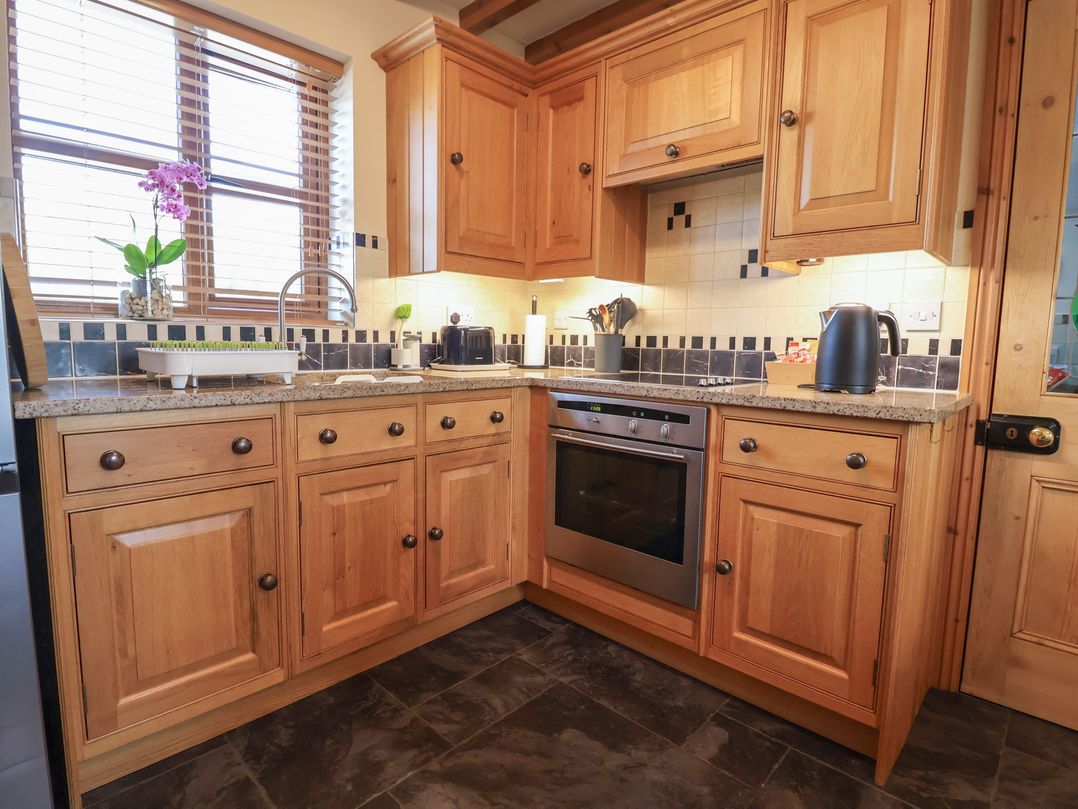 A kitchen with wooden cabinets and appliances at Ash Farm Cottage Lixwm near Caerwys