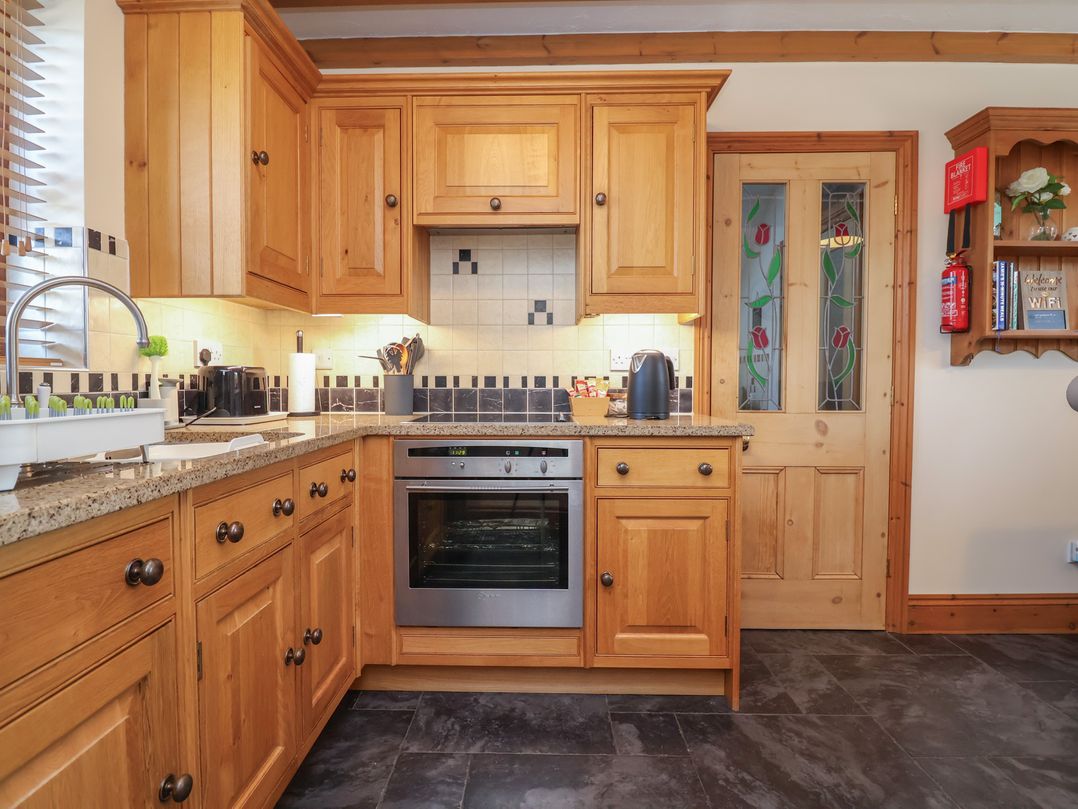 A kitchen with cabinets and appliances at Ash Farm Cottage in Lixwm near Caerwys