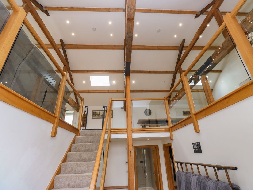 A hallway with stairs and glass railing at Upper House Barn in Delph