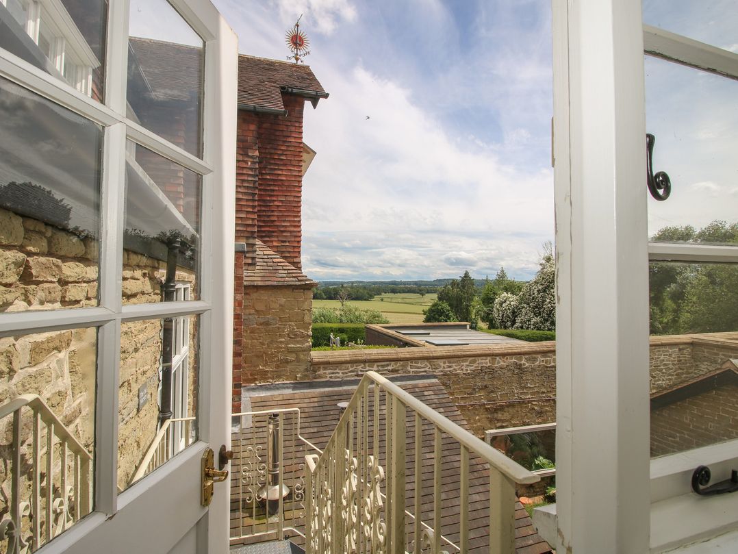 A balcony view with a stone wall and trees at The Old Nursery in Bourton near Much Wenlock