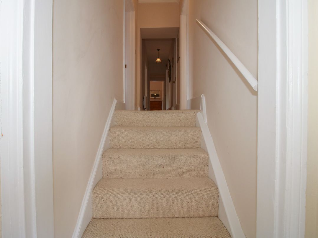 A staircase with a handrail leading into a hallway at The Old Nursery in Bourton near Much Wenlock
