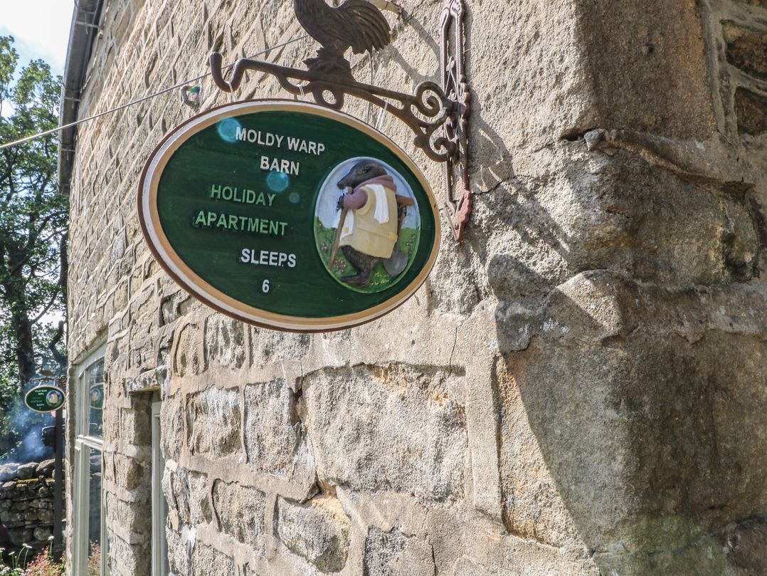 A sign for Moldy Warp Barn holiday apartment with details on sleeping capacity in Haworth