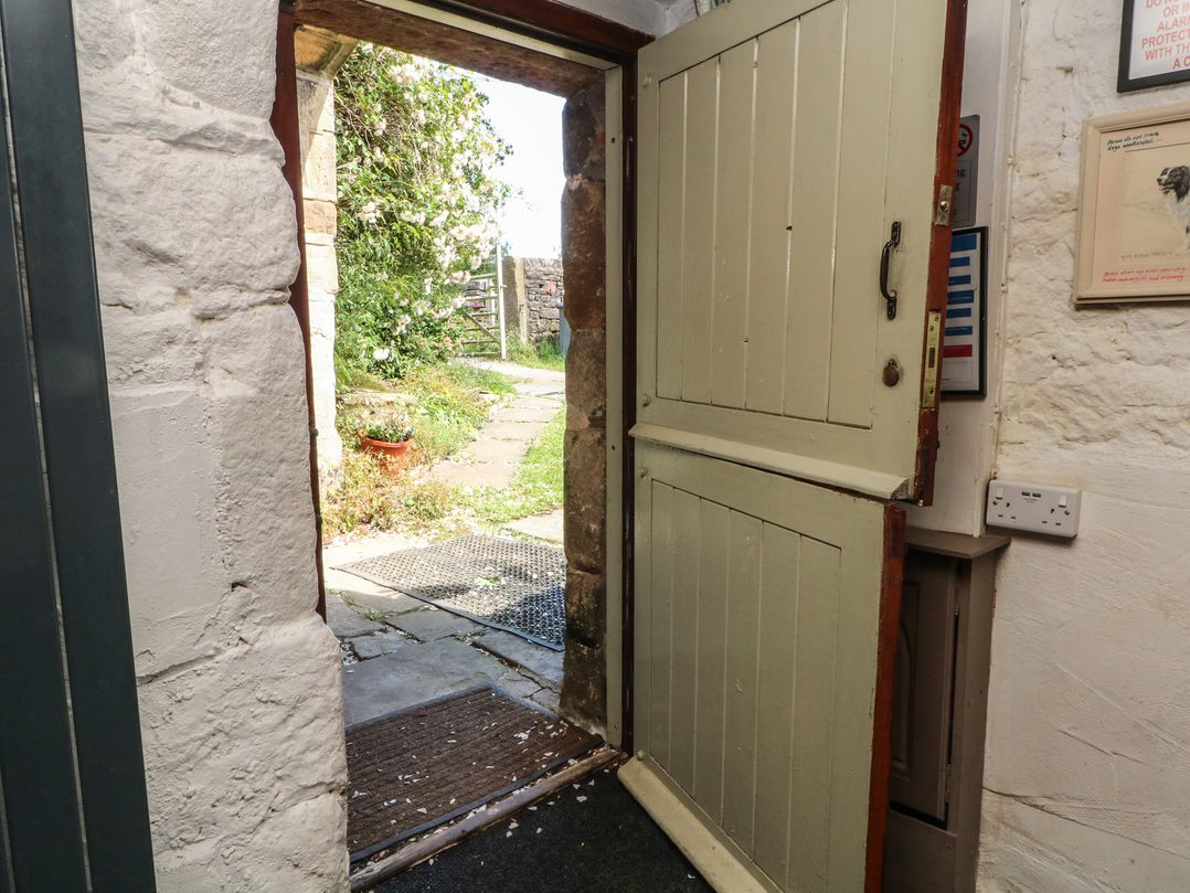 An entrance with an open door leading to a garden at Moldy Warp Barn in Haworth