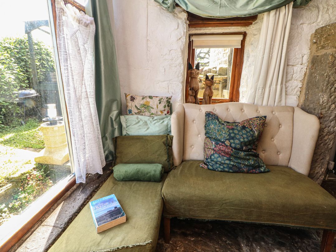 A living room with a sofa and book at Moldy Warp Barn in Haworth