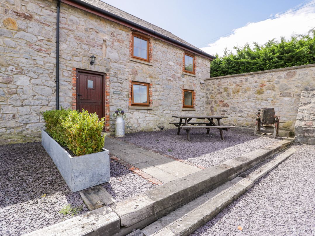 An outdoor area with a stone building, table, and seating at Stabal-y-Gwedd in Dolwen near Abergele