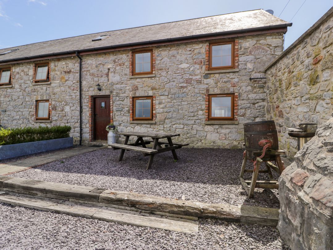 A stone wall house with a garden table and benches at Stabal-y-Gwedd in Dolwen near Abergele