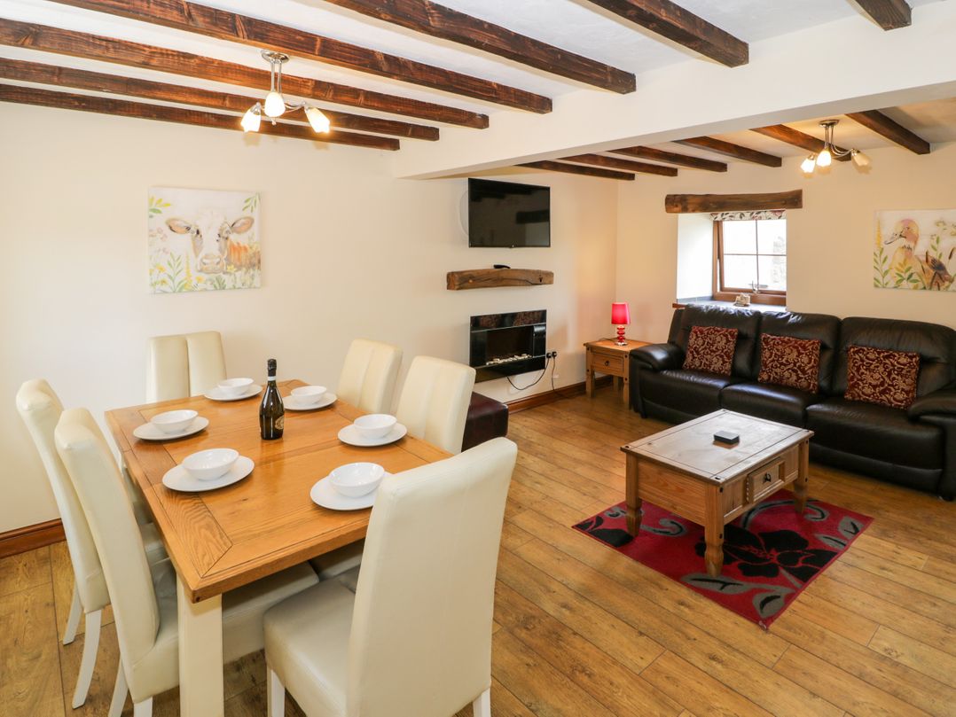 A living room and dining area with furniture and a television at Stabal-y-Gwedd in Dolwen near Abergele