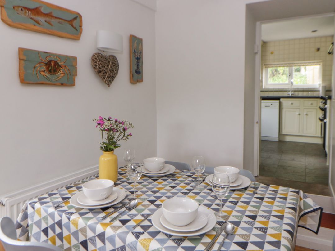 A dining room with a table set for meals at Little Barn Cottage in Dinas Cross, Pembrokeshire