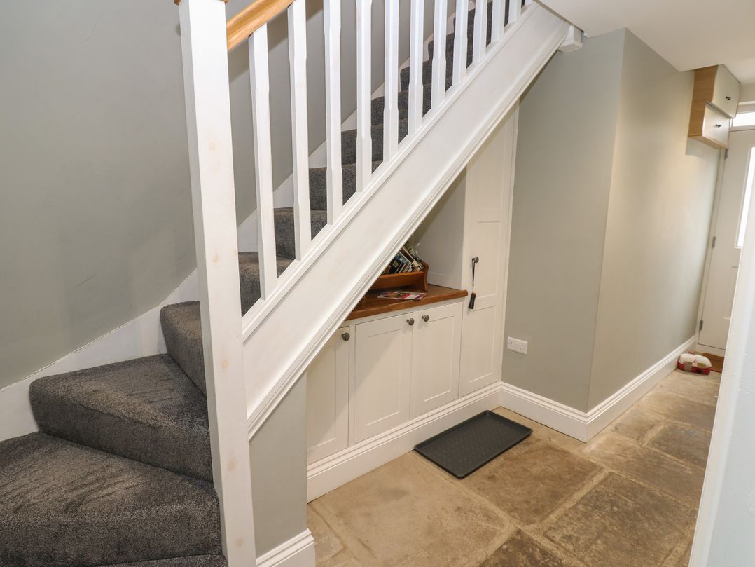 A hallway with a staircase and storage cabinet at White Lea in Reeth