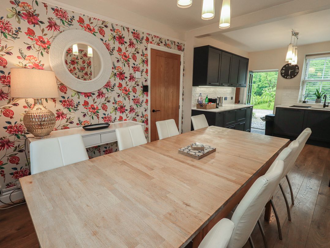 A dining room with a wooden table and white chairs at Newby Bridge House in Newby Bridge