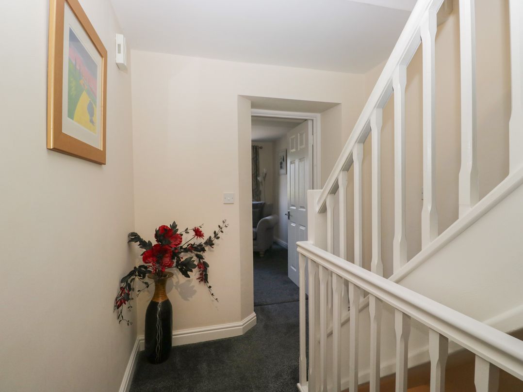 A hallway with a flower vase and staircase at Woodside West in Bowness