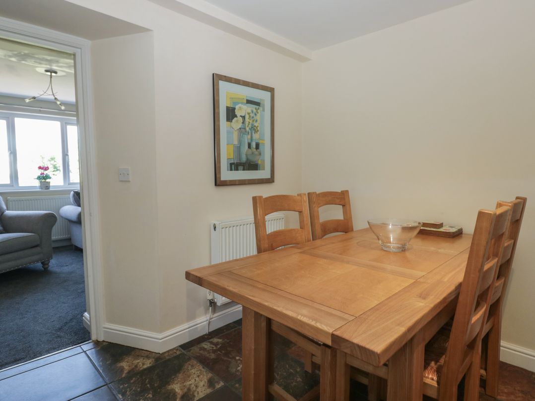 A dining room with a wooden table and chairs at Woodside West in Bowness