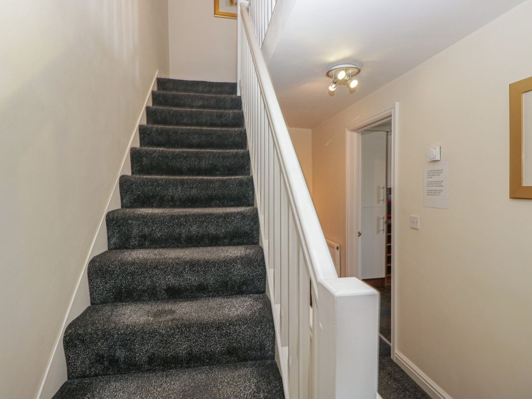 A staircase with a handrail and light fixture at Woodside West in Bowness