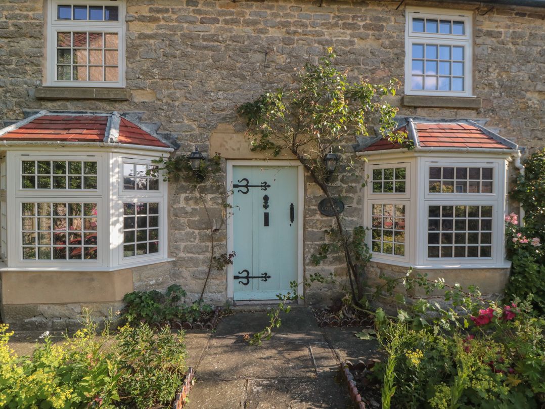 A stone cottage facade with green door and windows at Bute Cottage Lockton near Pickering