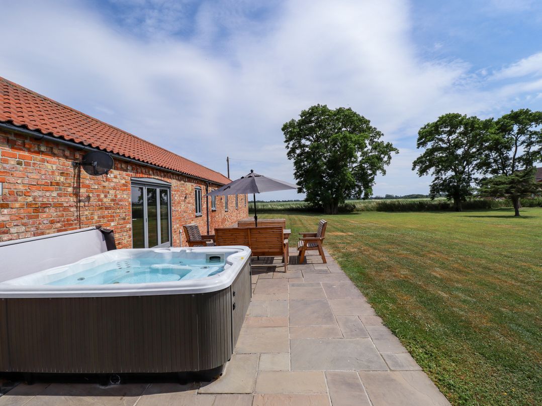 An outdoor area with a hot tub, patio furniture and grass at The Stables in Wrangle near Old Leake