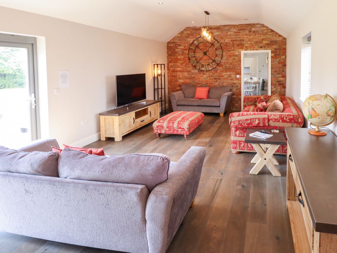 A living room with a television and sofas at The Stables in Wrangle near Old Leake