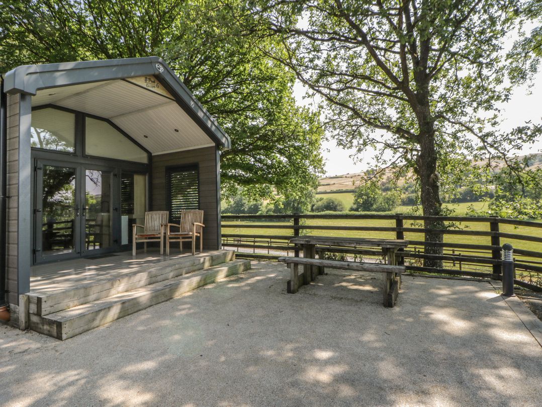 An outdoor area with wooden chairs and a table at Woodland Escape in Rhayader