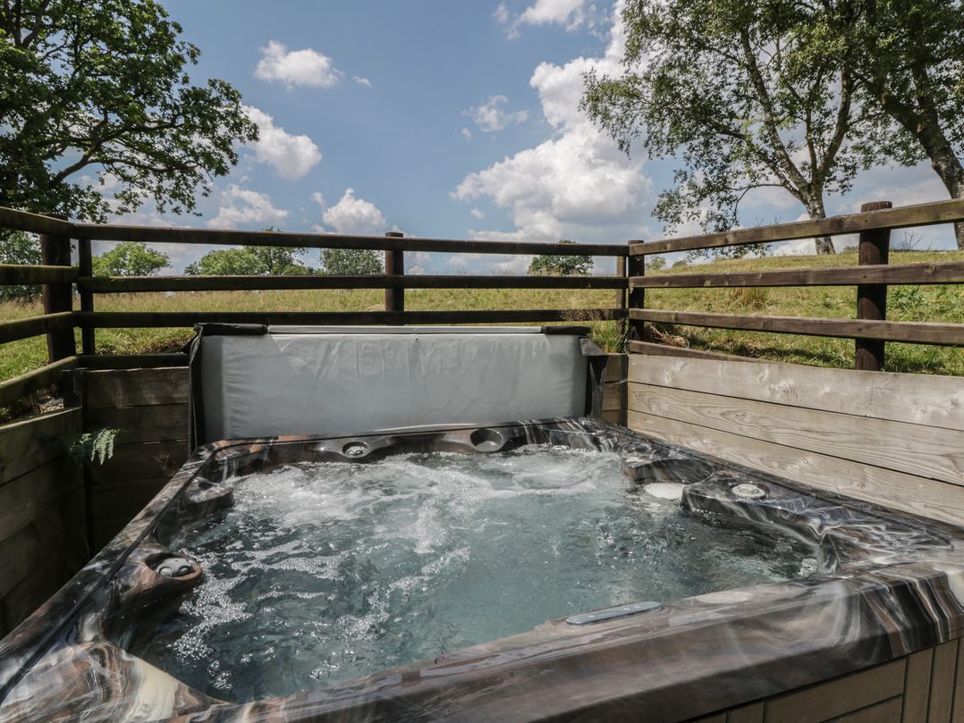 A hot tub with water and a fence at Woodland Escape in Rhayader