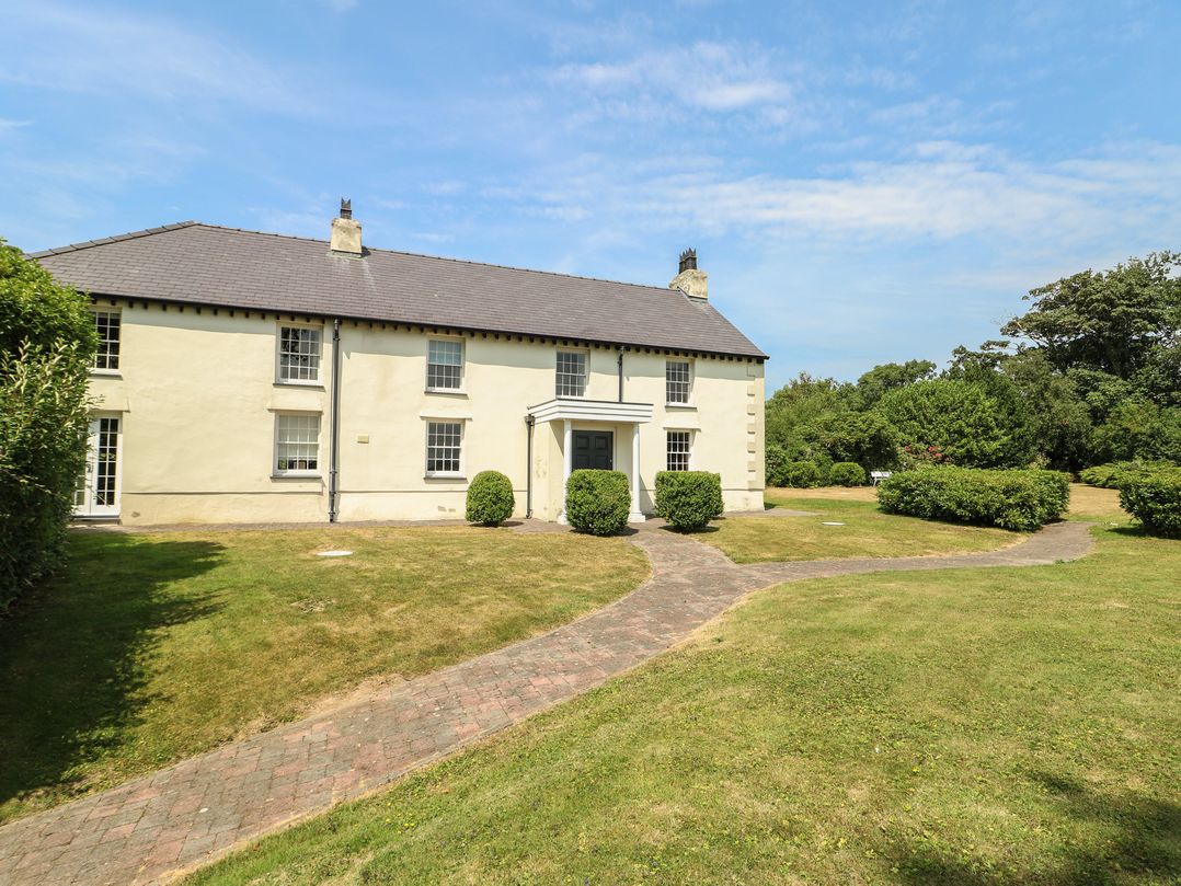 A house with a garden pathway and bushes at Clynnog House in Dwyran near Newborough