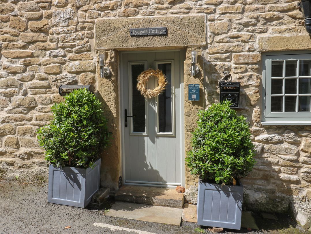 The entrance of Lydgate Cottage in Eyam with a front door and plants in planters