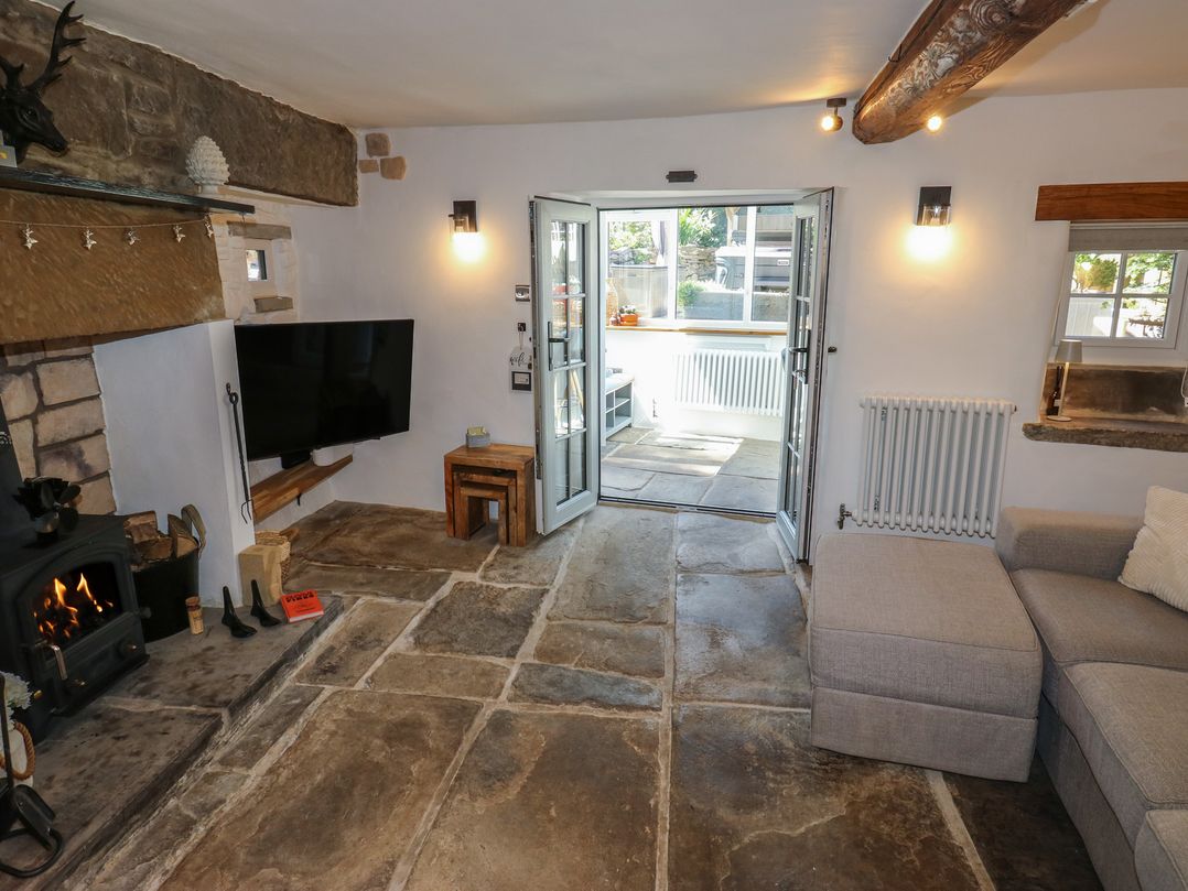 A living room with a fireplace and television at Lydgate Cottage in Eyam