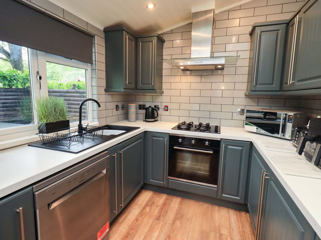 A kitchen with a sink, stove, and dishwasher at Rydal Lodge Grasmere 24, White Cross Bay near Windermere