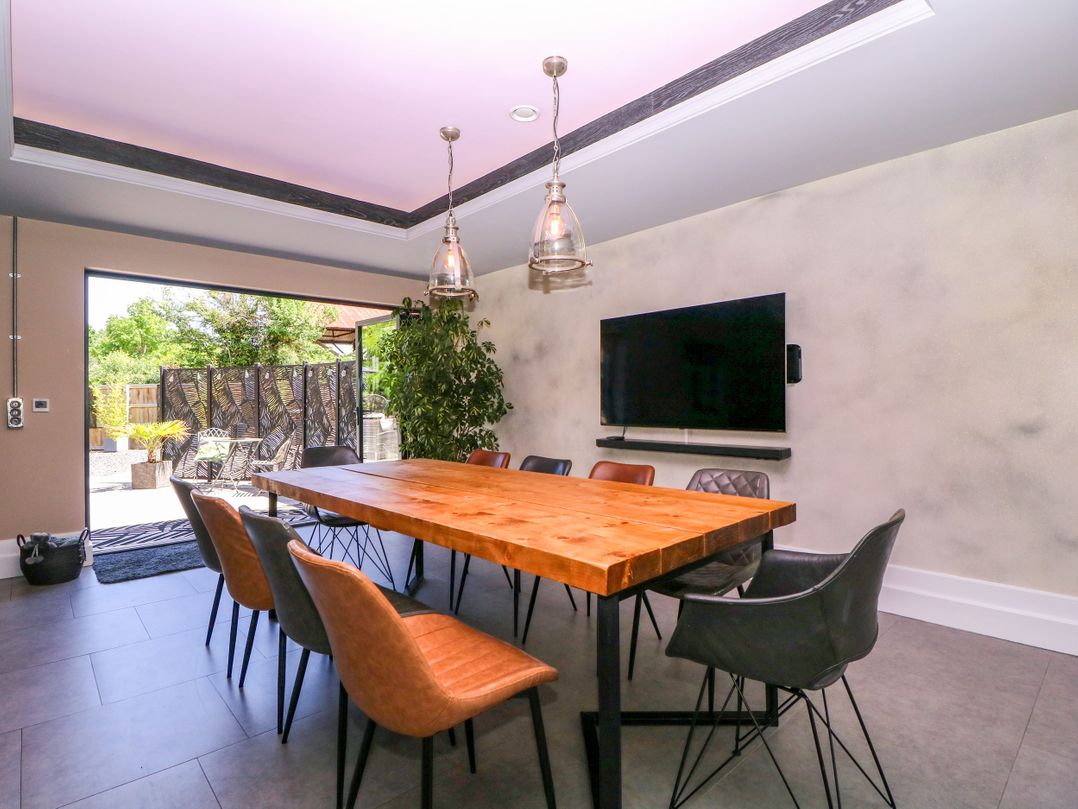 A dining room with a wooden table and chairs at Thornbury, Barnard's Green, Malvern