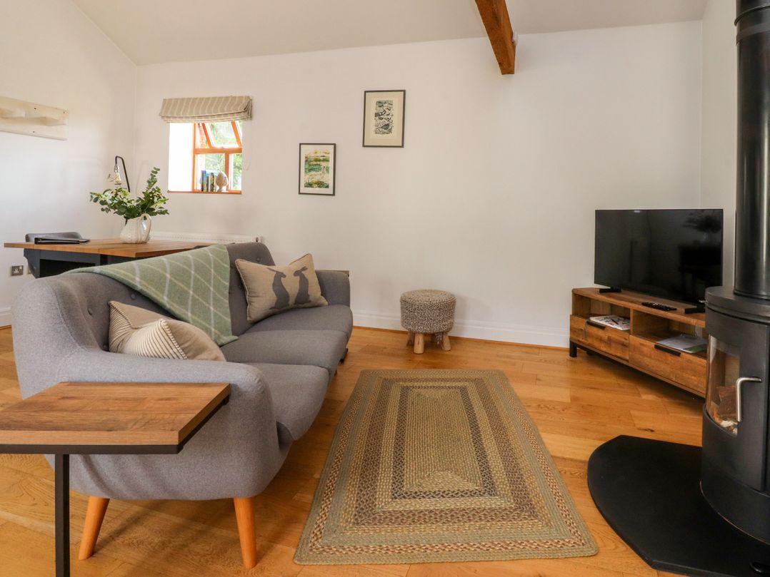 A living room with a sofa and television at The Stables in Hall Green near Walmer Bridge